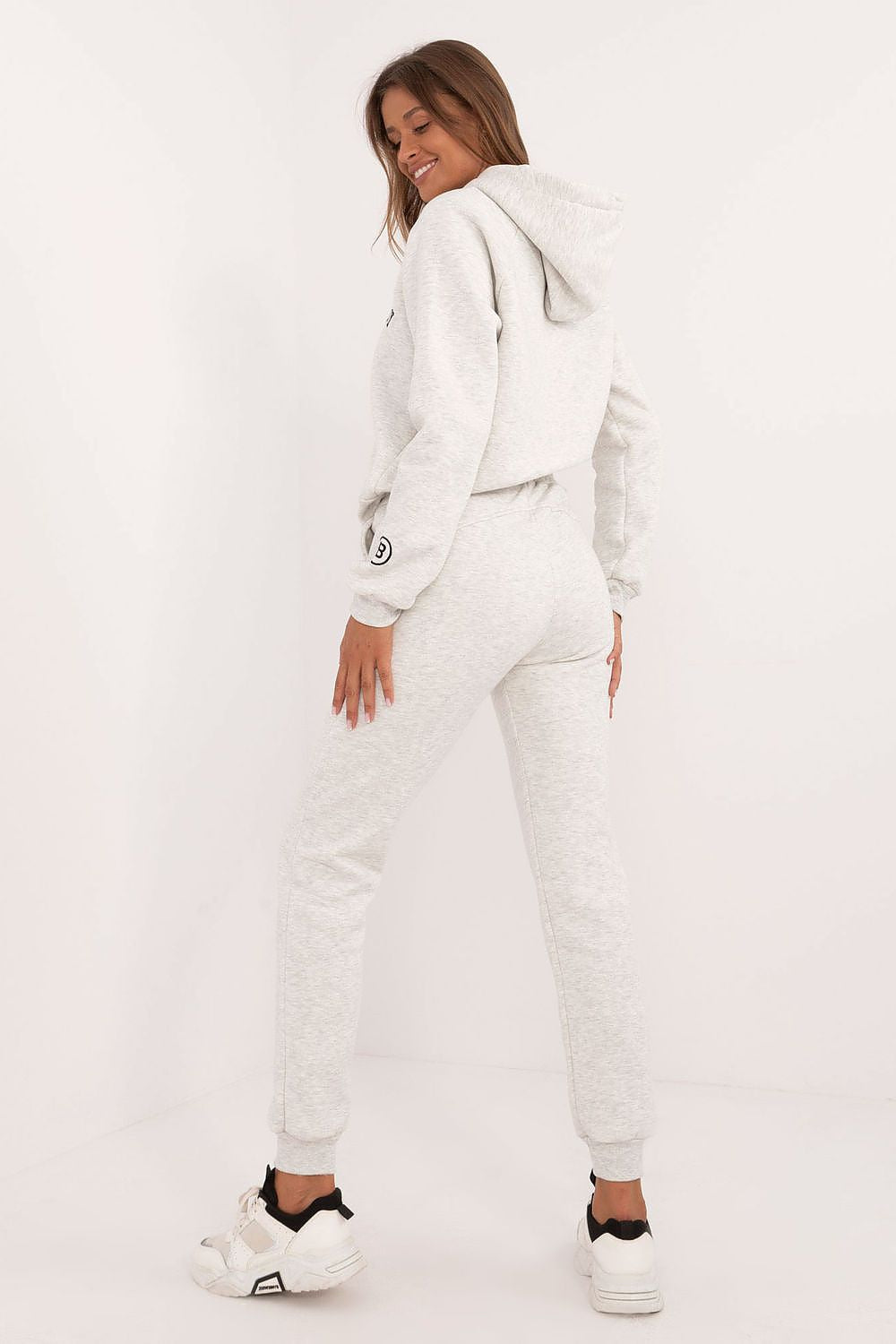 Woman wearing a light gray women's tracksuit set with hoodie and jogger pants from Factory Price