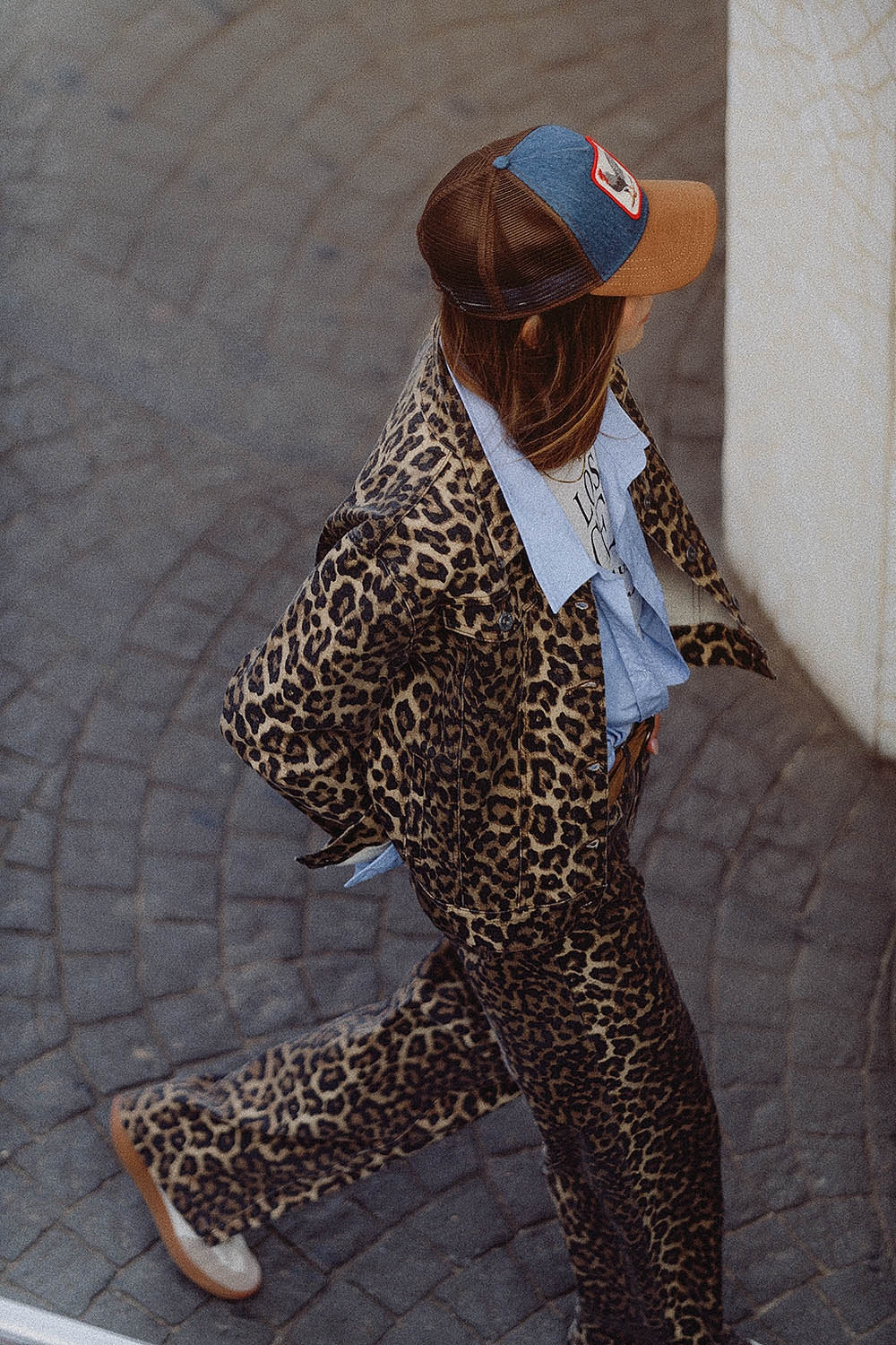 Woman wearing a brown animal print jacket for women paired with matching trousers and a blue shirt