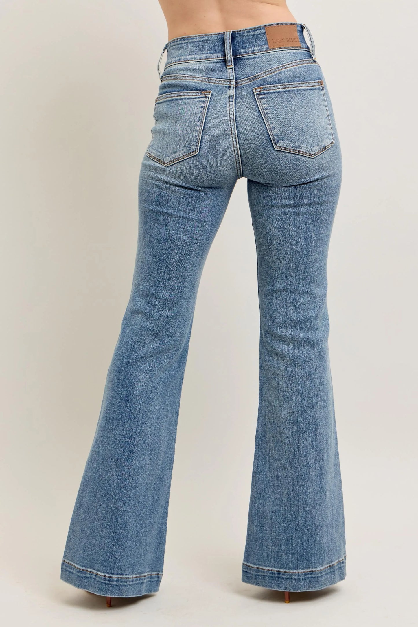 Judy Blue front seam denim pants in light blue wash with flared legs shown from the back