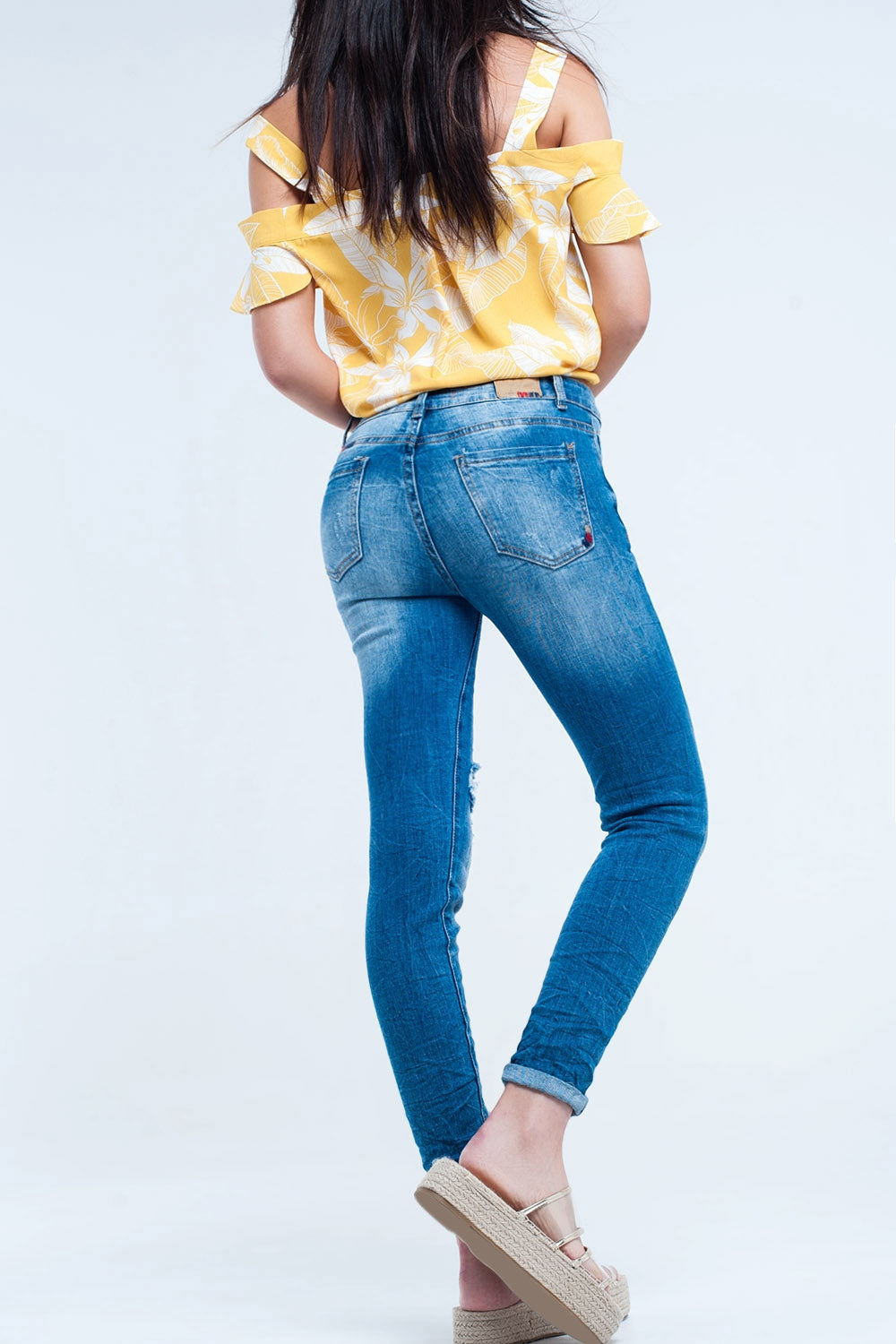 Jeans justo com lavagem média e rasgos