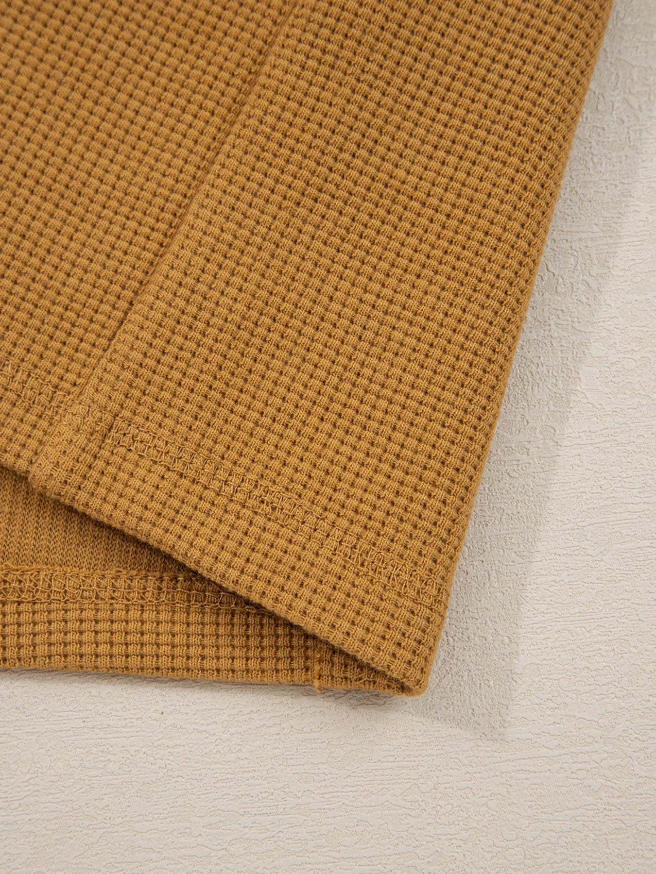 Close-up of an Oversized Textured Split Neck High Low Sweatshirt in warm brown with soft fabric detailing