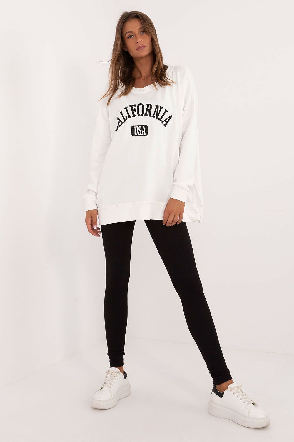 Woman wearing oversized sweatshirt and leggings set with white California sweatshirt and black leggings
