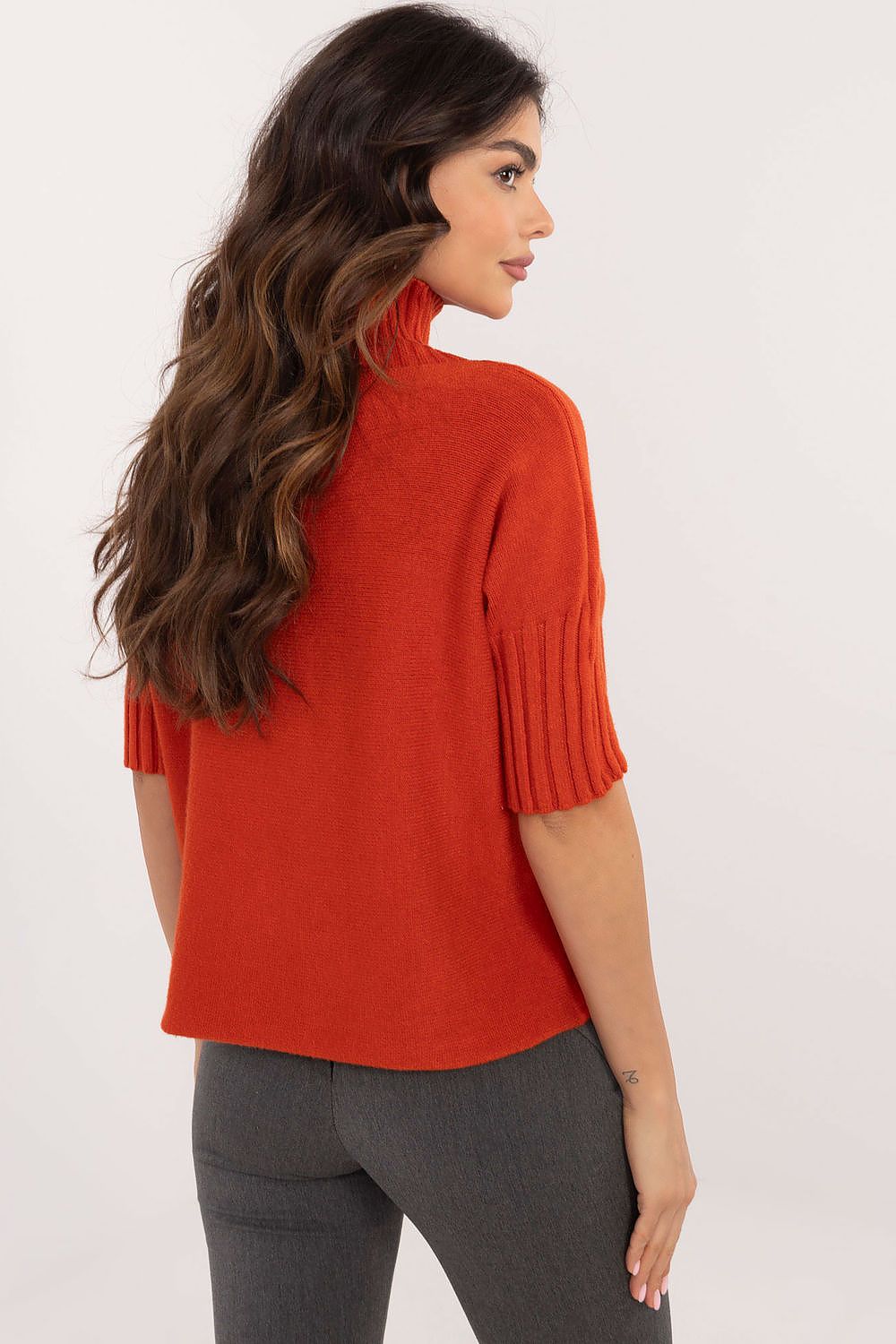 BFG short sleeve turtle neck sweater in rust orange worn by woman with wavy hair