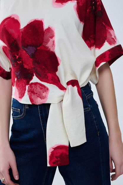 Blusa bege cortada com estampado floral tropical em vermelho atado na cintura