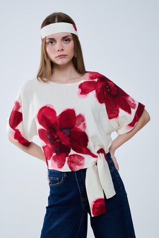 Blusa bege cortada com estampado floral tropical em vermelho atado na cintura