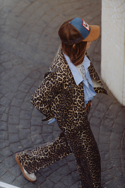 Woman wearing a brown animal print jacket for women paired with matching trousers and a blue shirt