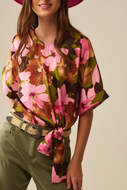 Top com nó floral e fundo verde em tecido acetinado